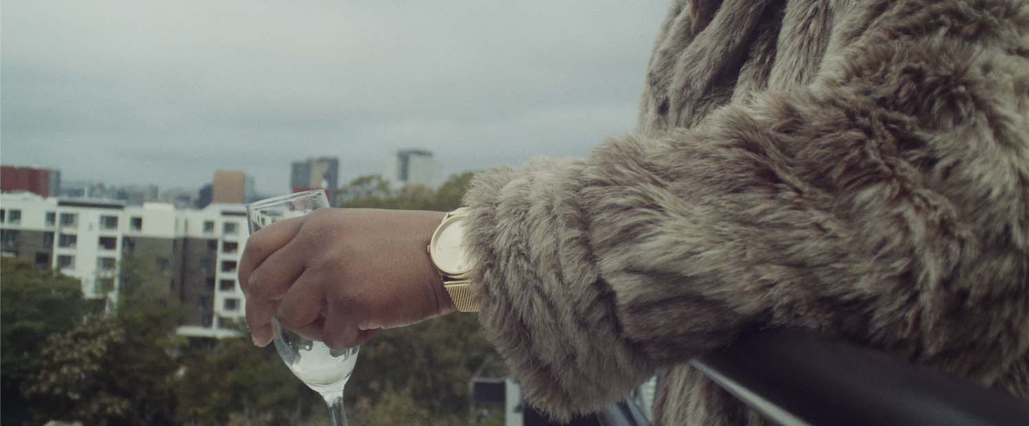 Close up shot of OOMPA holding champagne glass with a gold watch and fur coat on a rooftop overlooking over the Roxbury skyline | Nicolas Andrew Visuals