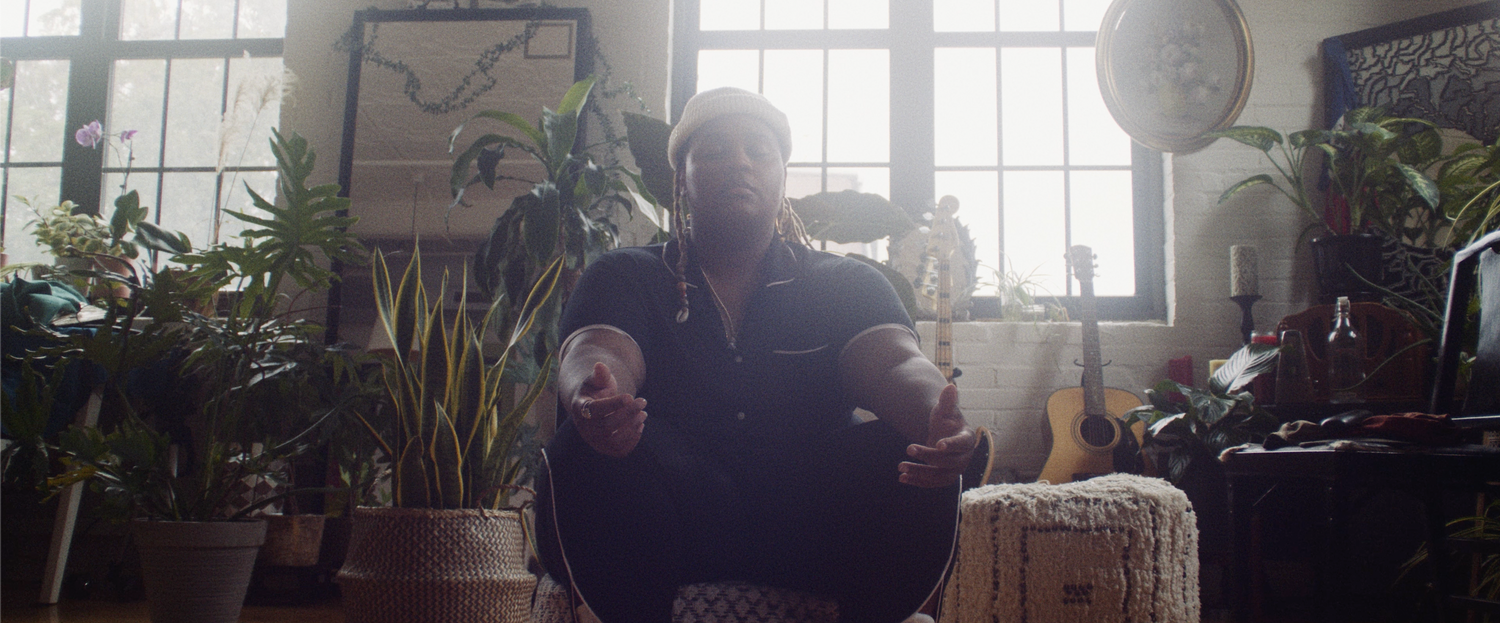 Full shot of OOMPA meditating with plants, guitars, and decor in the background | Nicolas Andrew Visuals